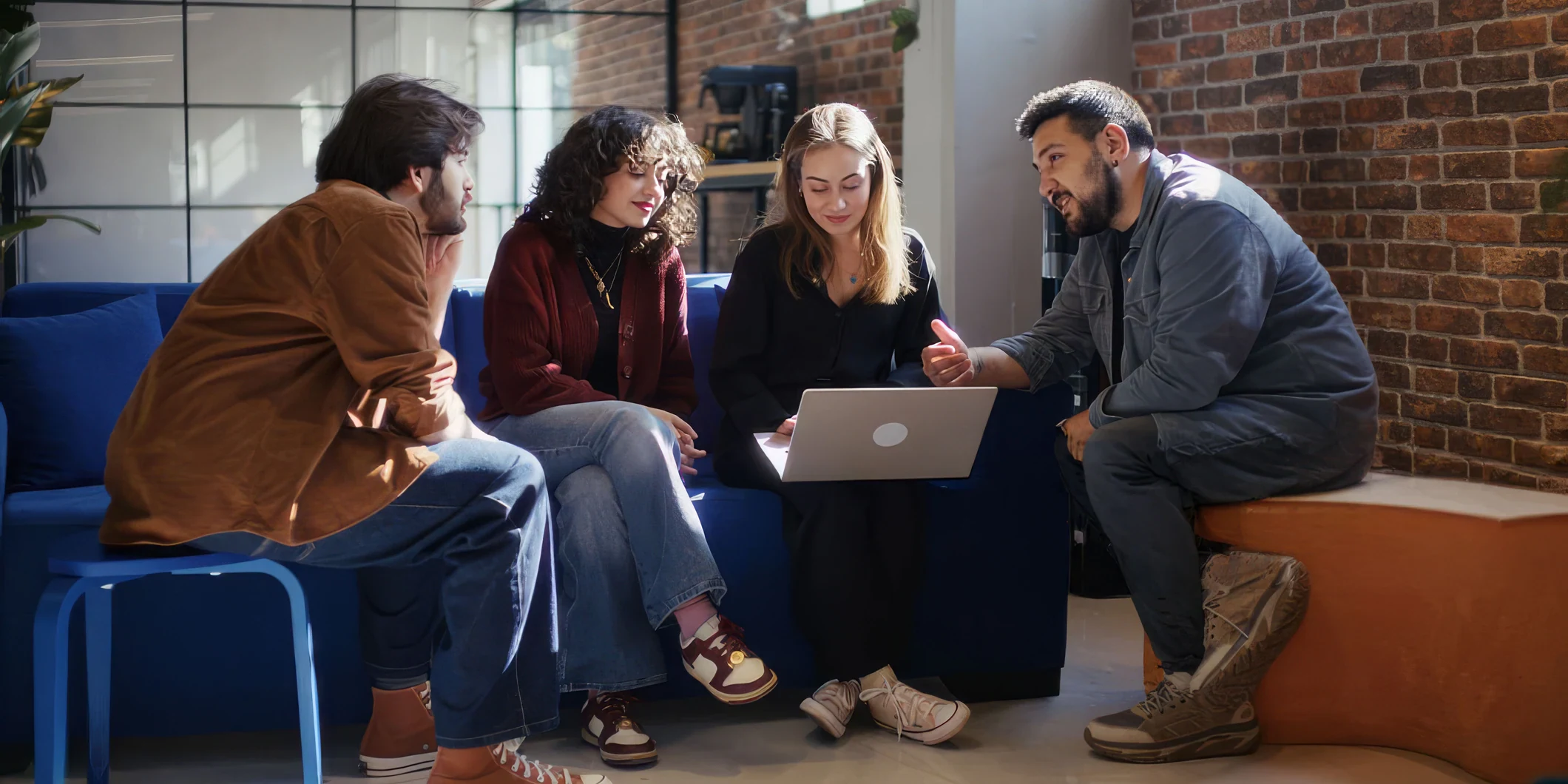 Colleagues working together around a laptop in a shared workspace